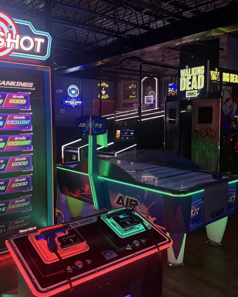 Big Shot shooting game and an air hockey table glowing in neon