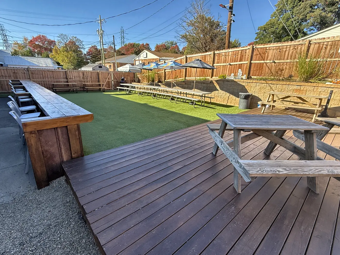 The Patio Oasis from the back deck: picnic tables, turf and umbrellas along the fence